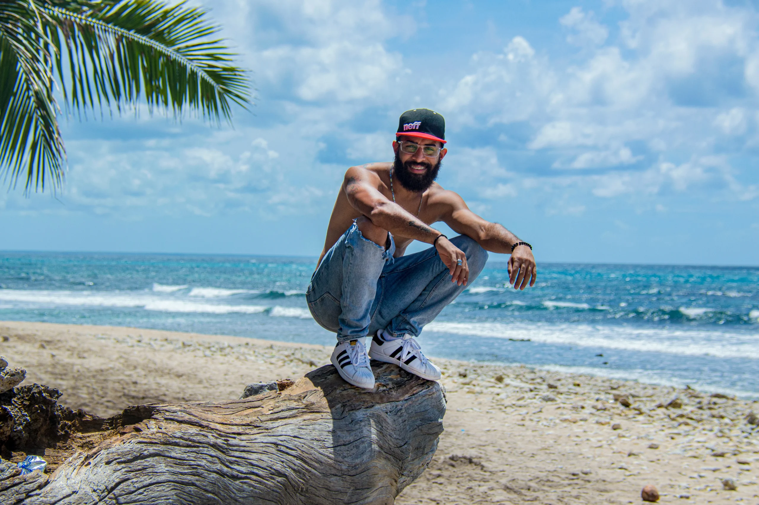 En una playa de La Romana. Foto por <a href="https://unsplash.com/@germanjorge?utm_source=unsplash&utm_medium=referral&utm_content=creditCopyText">German Jorge</a> on <a href="https://unsplash.com/photos/man-in-blue-denim-jeans-and-black-cap-sitting-on-tree-trunk-on-beach-during-daytime-dBLKKYpaADc?utm_source=unsplash&utm_medium=referral&utm_content=creditCopyText">Unsplash</a>