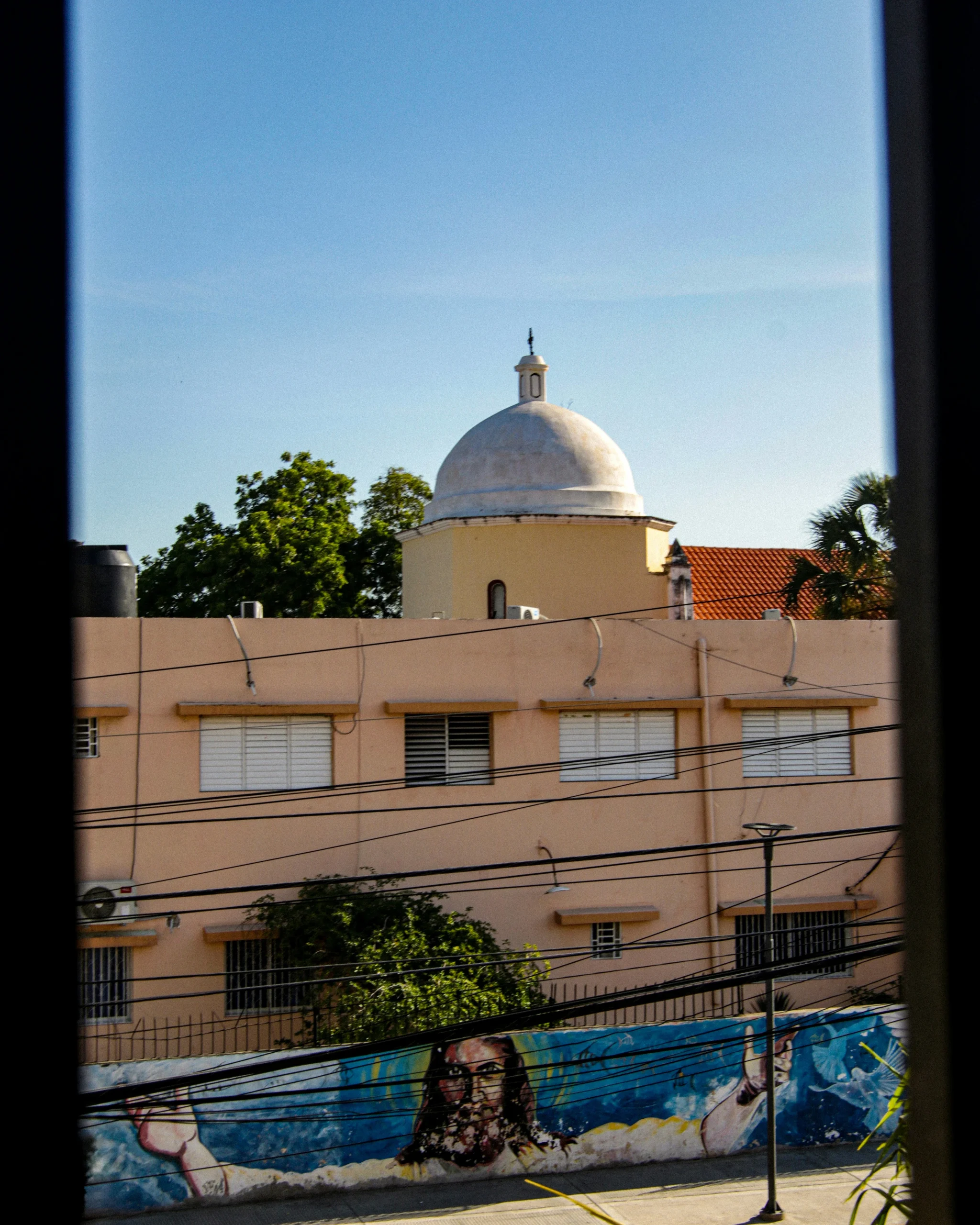 San José de Ocoa. Foto por <a href="https://unsplash.com/@fotoso?utm_source=unsplash&utm_medium=referral&utm_content=creditCopyText">Luis Beeves</a> on <a href="https://unsplash.com/photos/a-view-of-a-building-through-a-window-yk_9wQ0u1Y8?utm_source=unsplash&utm_medium=referral&utm_content=creditCopyText">Unsplash</a>