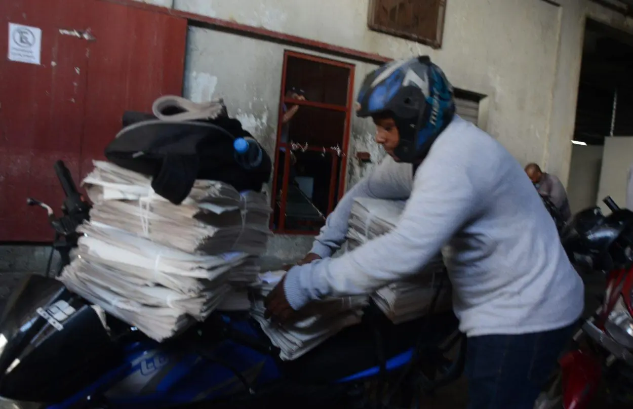 Un repartidor acomoda los periódicos que van a las calles. Cortesía de bonaocity.com.do. | NOTICIARIO RD Un repartidor acomoda los periódicos de la actualidad que van a las calles. Cortesía de bonaocity.com.do.