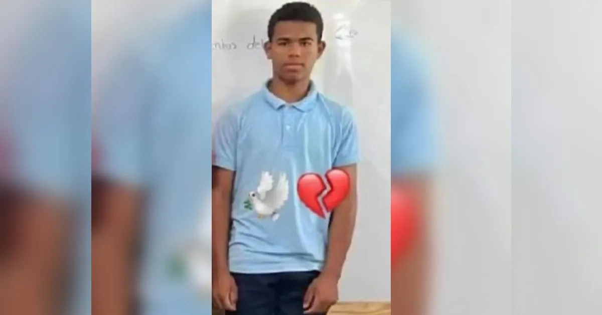 Teenage boy in a light blue polo shirt stands in a classroom, with a dove emoji and a broken-heart emoji over his chest.