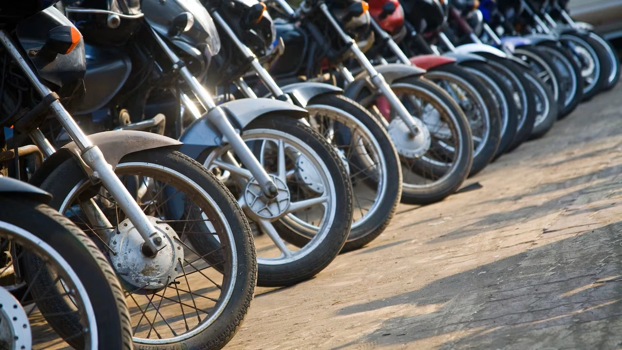 Row of motorcycles parked along a street, front wheels close together.