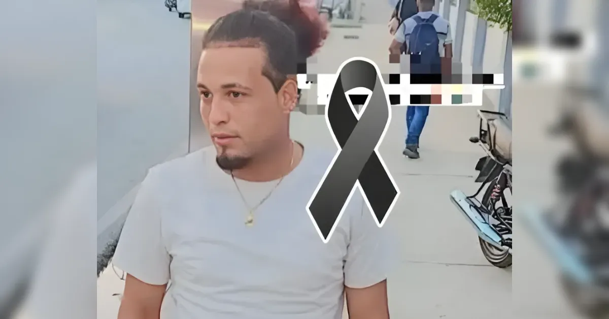 Young man in a white T-shirt sits by a sidewalk; a large black ribbon graphic signals mourning or tribute.