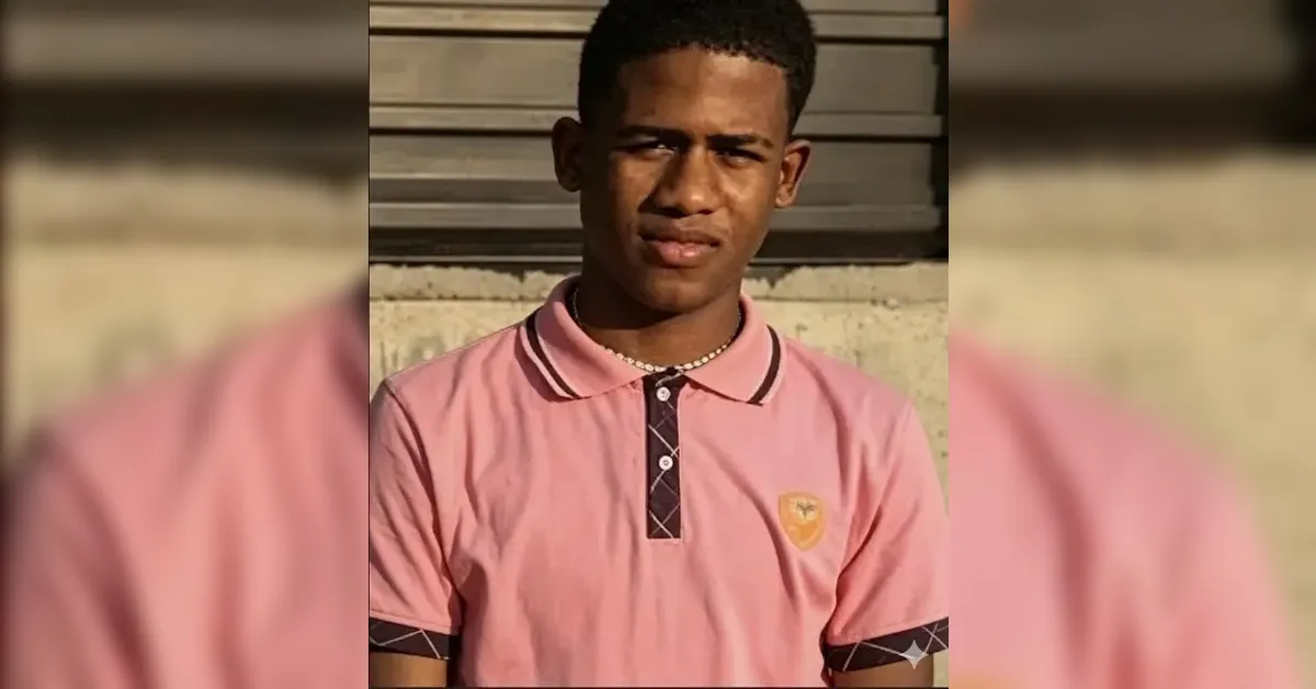 Portrait of a young man wearing a pink polo shirt with a dark placket, standing outdoors near a concrete wall.