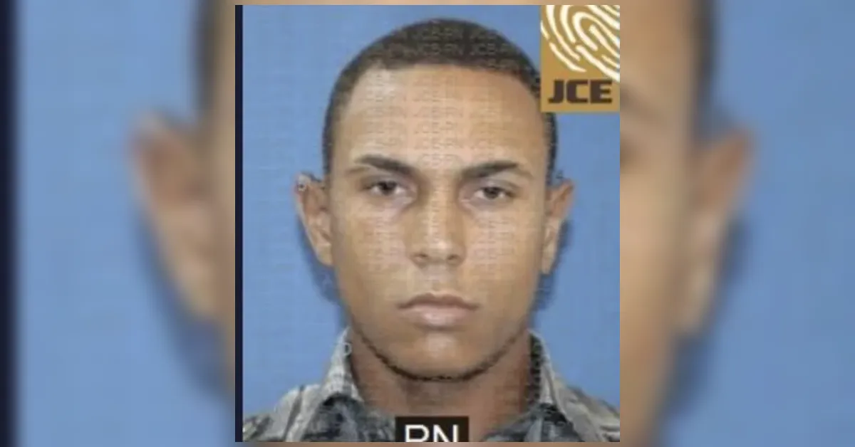 Mugshot of a man facing the camera against a blue background; neutral expression, plaid shirt visible.