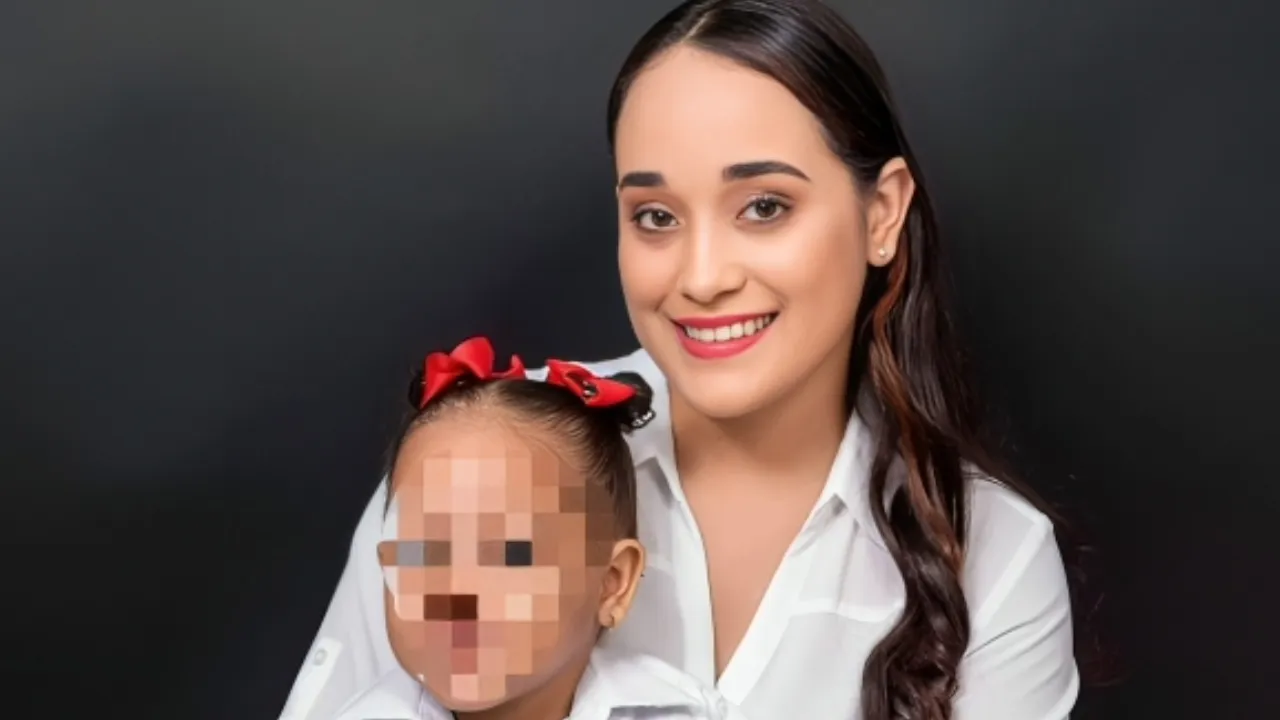 Smiling woman in a white blouse poses with a toddler whose face is pixelated, against a dark background.