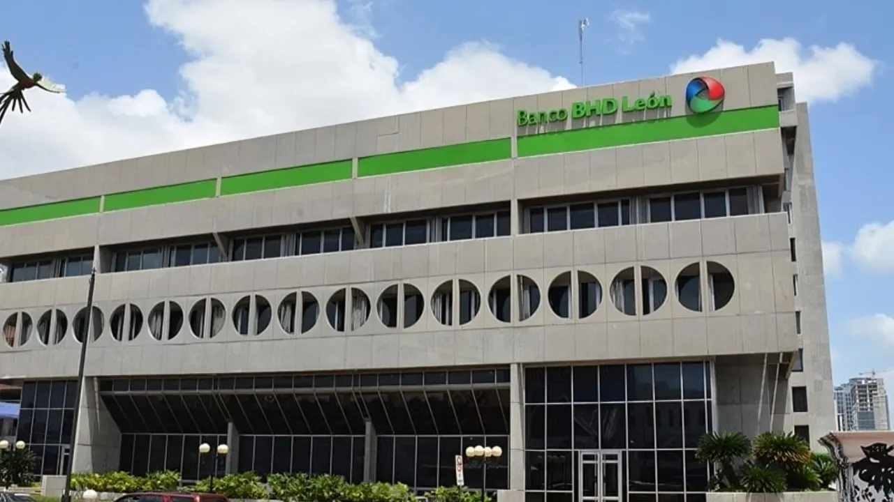 Exterior view of Banco BHD León bank building with a green stripe against a blue sky.