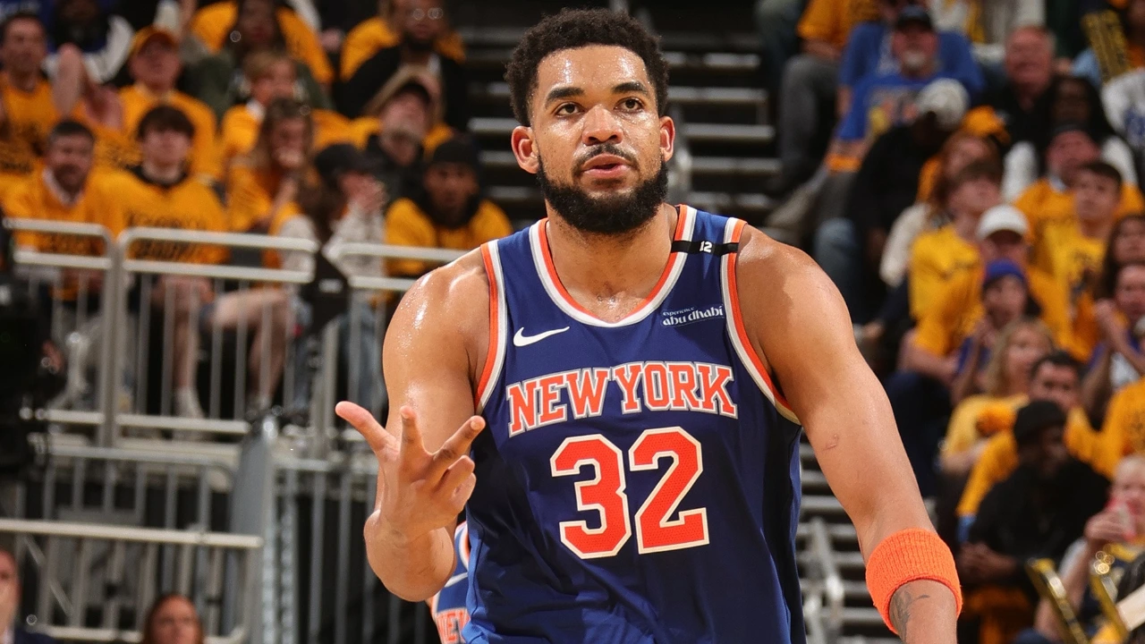 New York Knicks basketball player wearing #32 on court, gesturing with his right hand as fans watch behind him.