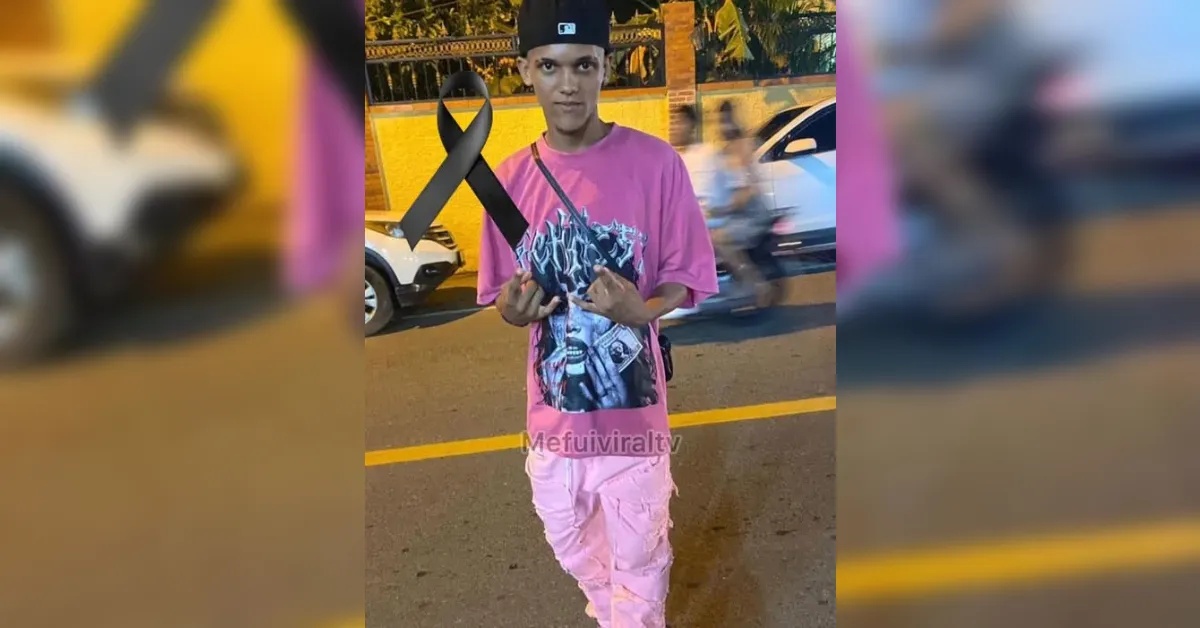 Young man in pink outfit on a street holds a large black awareness ribbon.