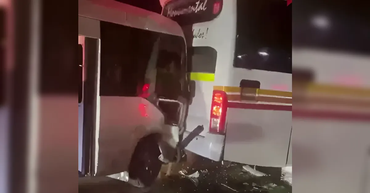 White bus and a white SUV have collided; the bus rear end is crumpled, debris on the ground nearby, night scene with red tail lights visible