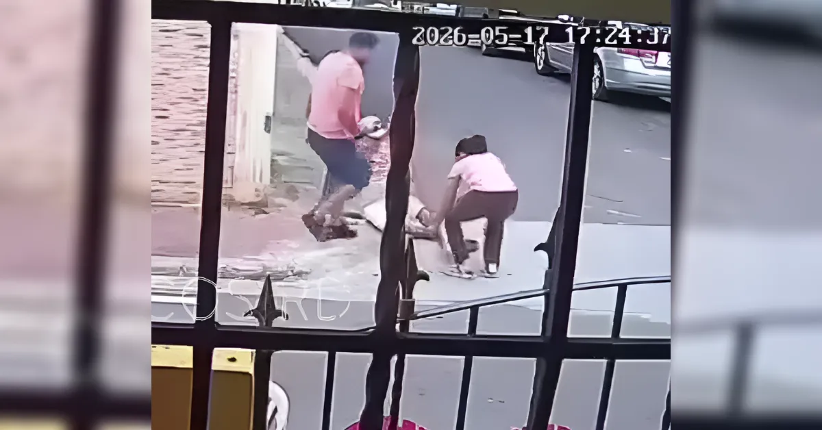 Surveillance video of two adults on a sidewalk near a doorway, with one bending down toward something on the ground.