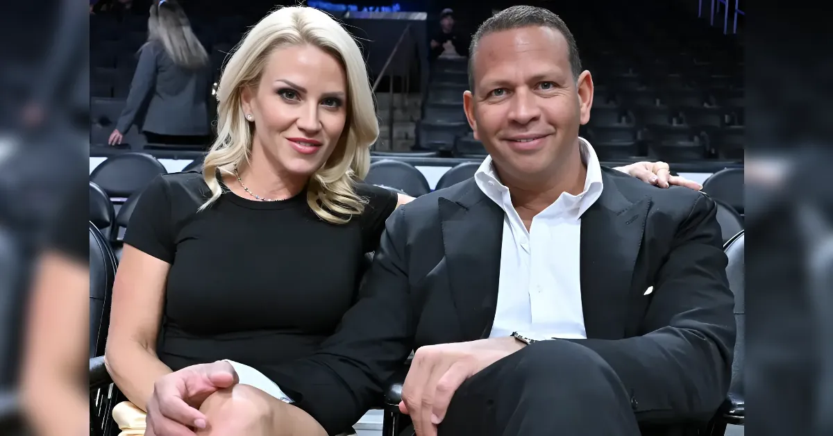 Smiling couple seated in a dark arena, dressed in black formal attire.