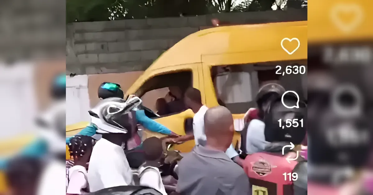 Crowd gathers around a yellow van on a street, with motorbikes nearby and a person in white with blue sleeves reaching toward the van.