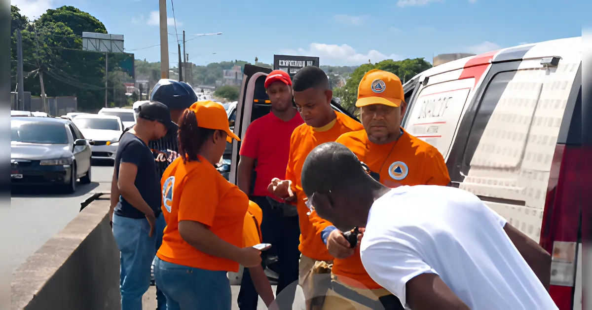 Emergency responders in orange uniforms stand on a highway shoulder around a white van, coordinating amid traffic.