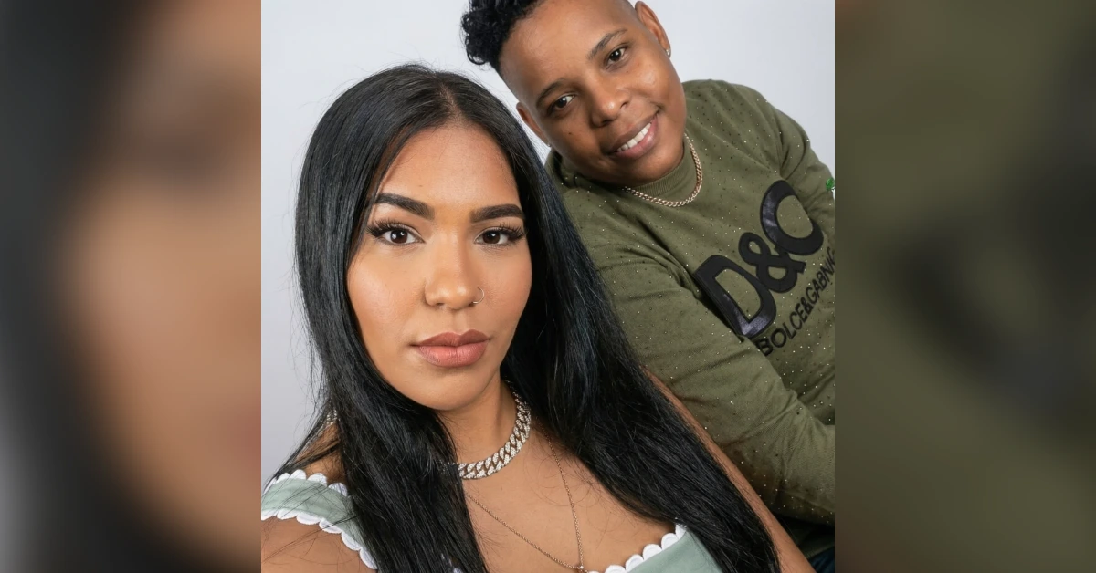 Two friends posing for a close selfie: a woman with long black hair in the foreground and a man in a green D&G shirt smiling in the background.
