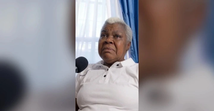 Older Black man with gray hair wearing a white polo speaks into a microphone in a room, suggesting an interview or public address.