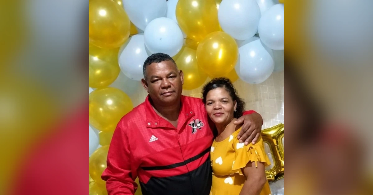 Couple posing together at a celebration with gold and white balloons in the background.