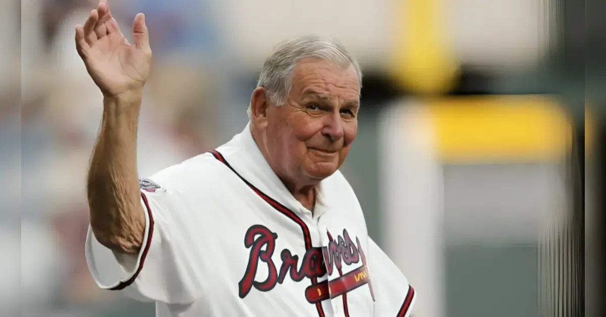 Older man in a white Braves jersey waves to the crowd.