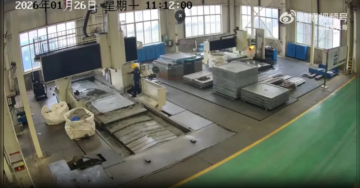 Industrial factory floor with large metal stamping machines, stacks of metal sheets, and workers in hard hats.