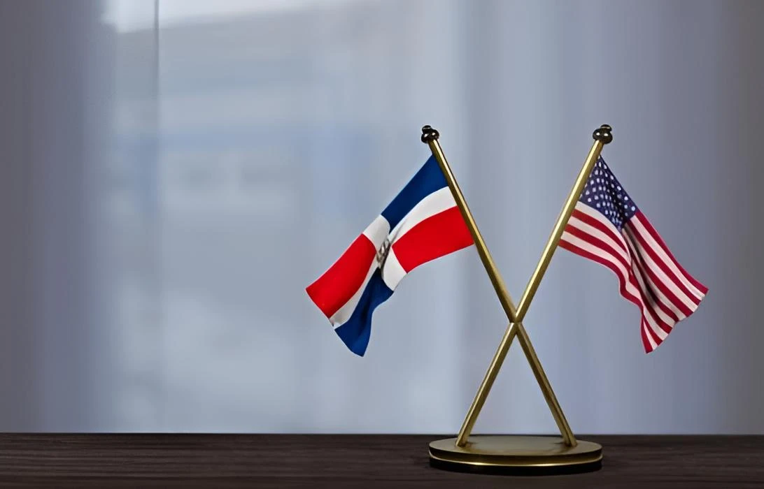 Two crossed national flags on a gold stand: UK flag on the left and U.S. flag on the right, planted on a wooden surface.