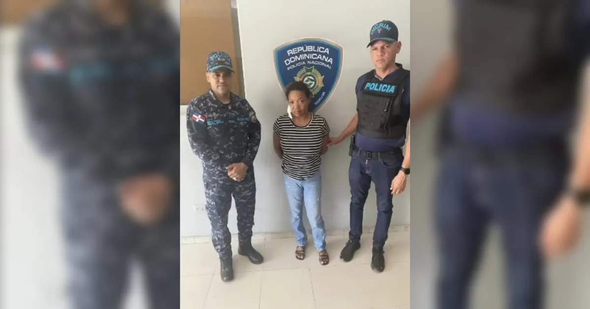 Arrest scene: a woman in a striped shirt stands between two Dominican police officers in front of a police shield.