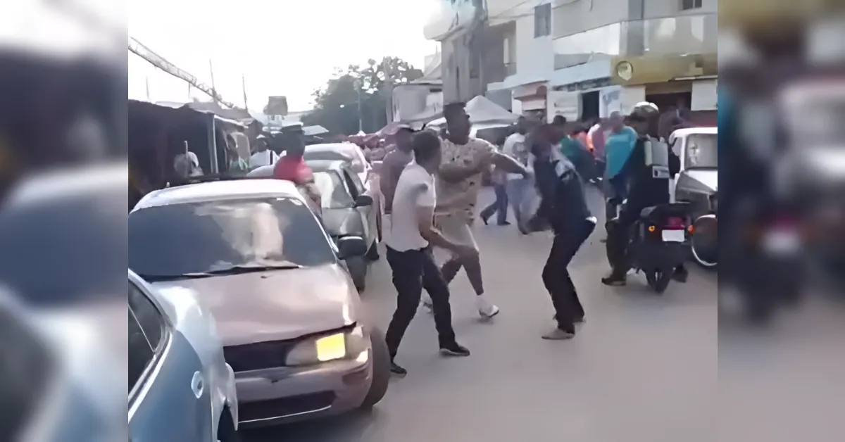 People dancing in the middle of a busy street between parked cars as bystanders watch in a crowded market area.