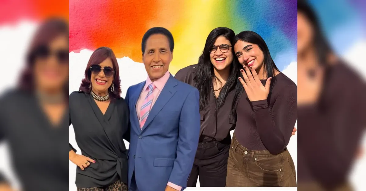 Four adults posing and smiling in front of a rainbow-colored wall; man in a blue suit center, flanked by two women on either side.