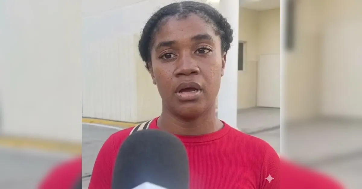 Woman in a red shirt being interviewed outdoors, microphone held toward the camera.