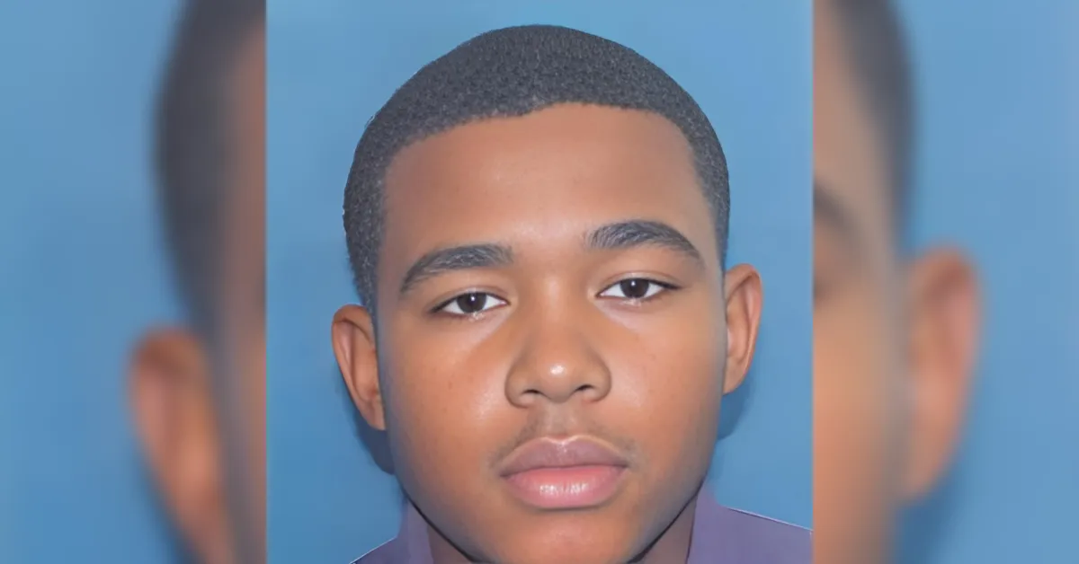 Mugshot-style close-up of a young man with short hair against a blue backdrop?