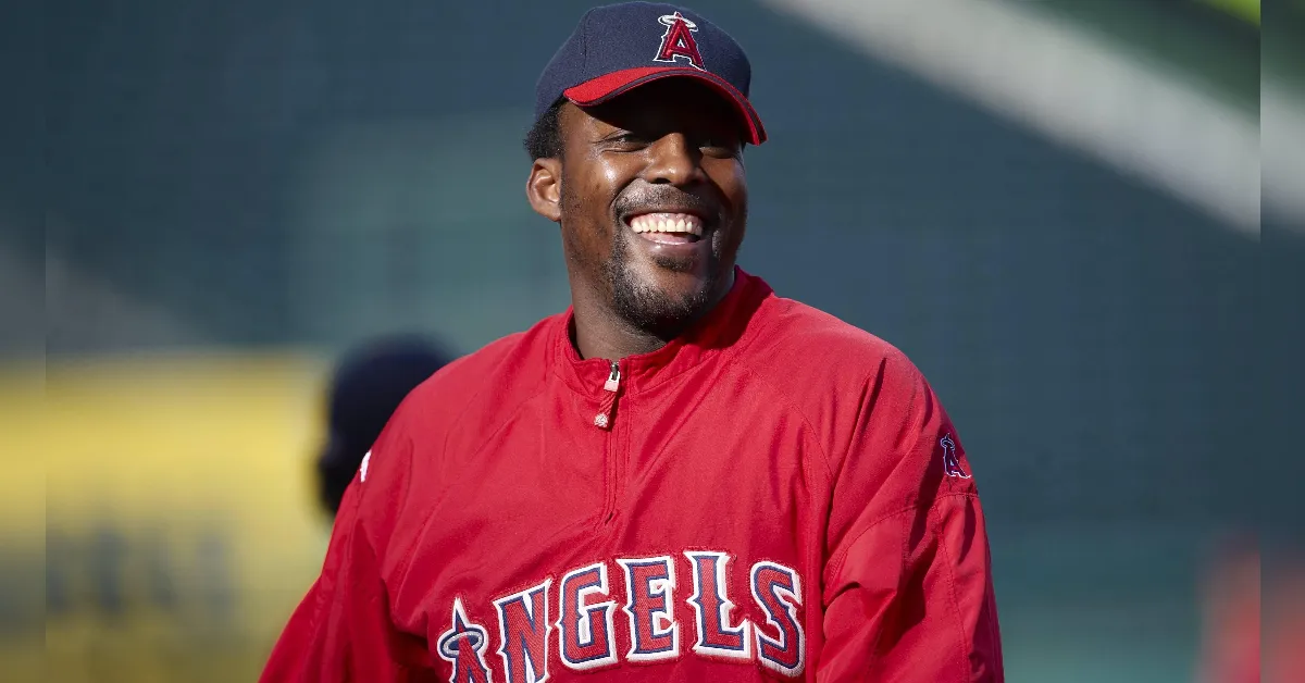 Smiling man in a red Angels jacket and cap outdoors on a sunny day