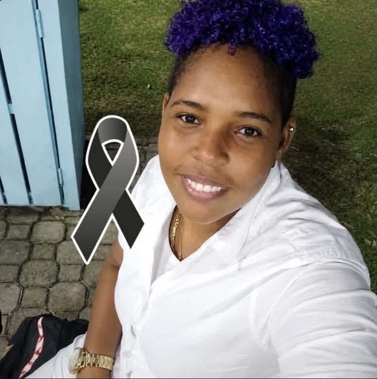 Smiling woman with purple hair taking a selfie outdoors; a gray awareness ribbon overlays her chest area.