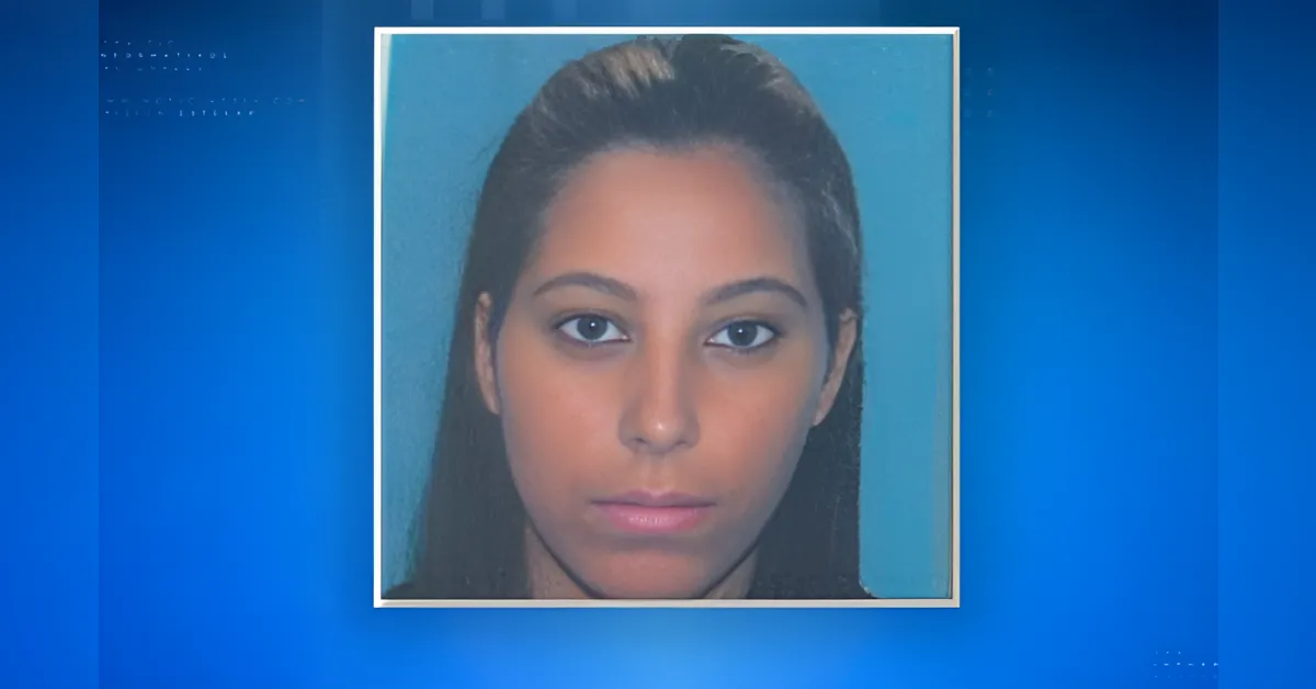 Mugshot-style headshot of a young woman with dark hair against a blue backdrop and a neutral expression, framed in a square.