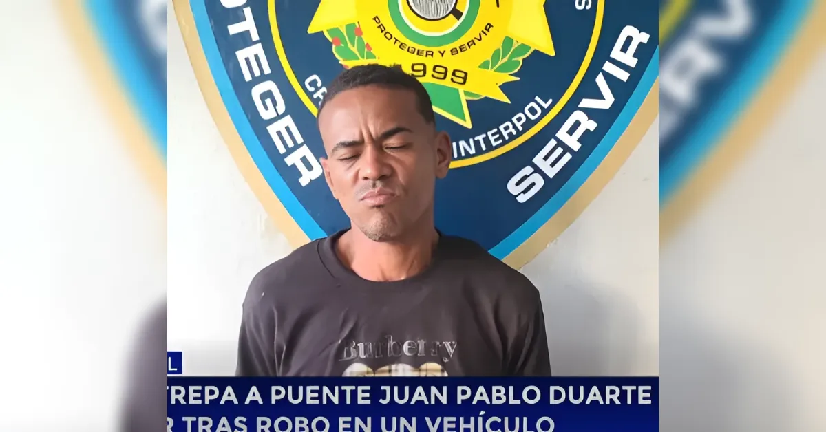 Man with a pained expression stands in front of a blue police crest, with a Spanish news ticker at the bottom.