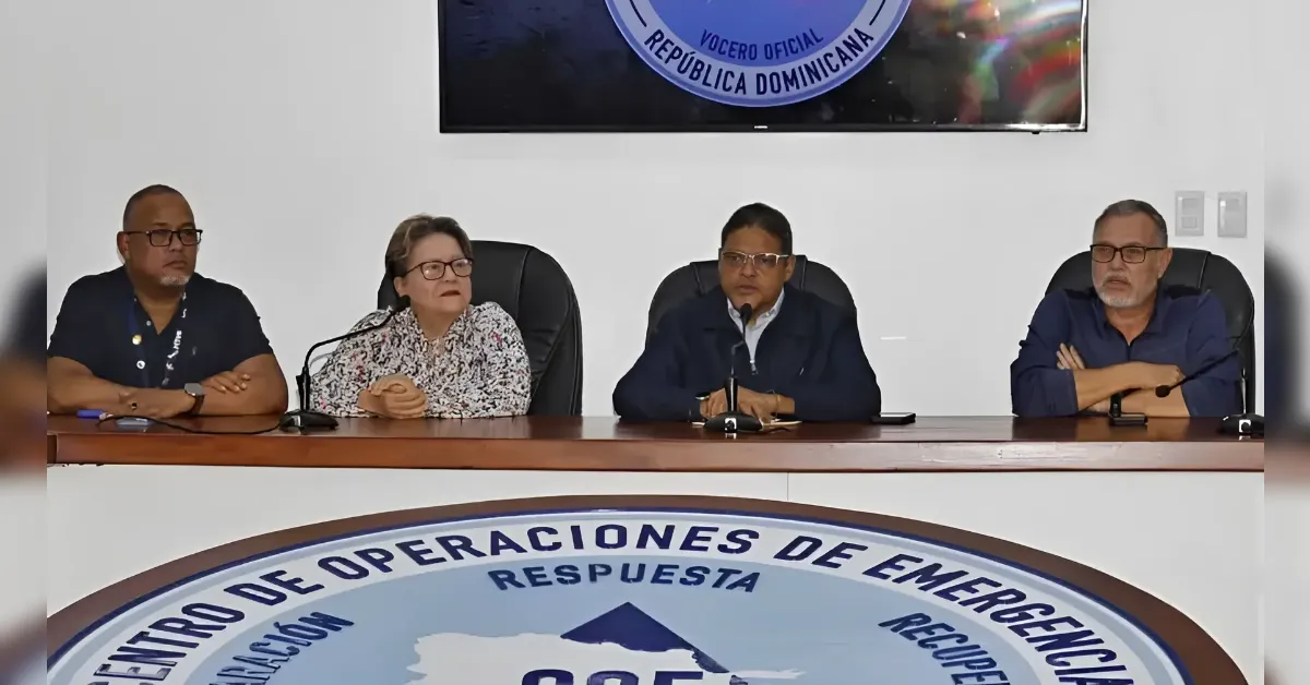 Panel of four officials seated at a press conference table, with a large Dominican Republic seal in the foreground display