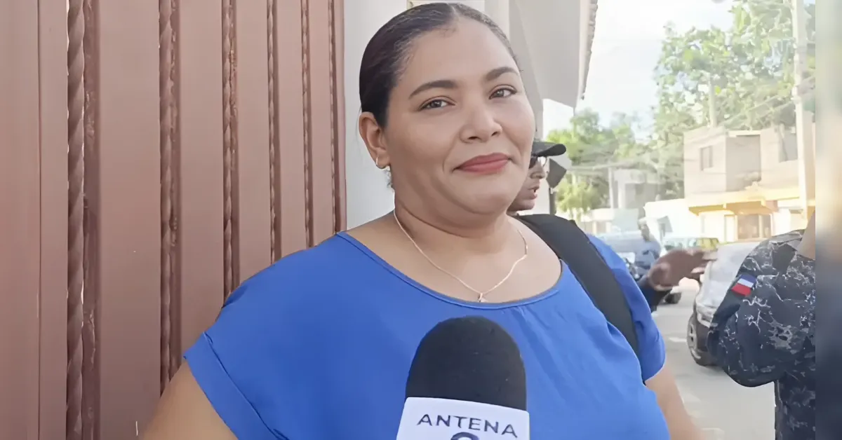 Smiling woman in a blue blouse being interviewed on a sidewalk, microphone labeled ANTENA near her.