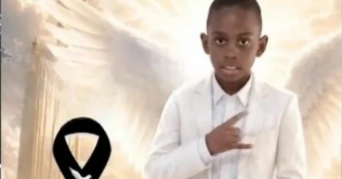 Young boy in a white suit posing for a photo, with his right hand forming a rock-on gesture.