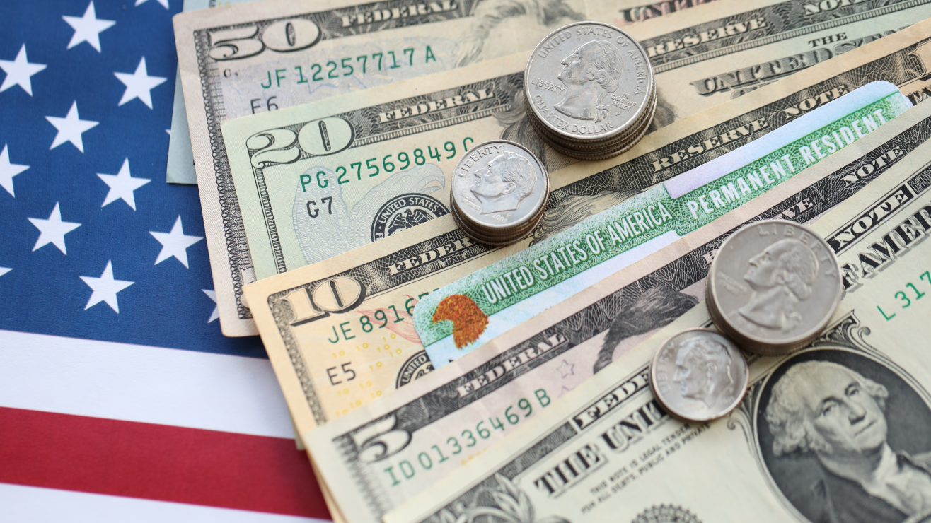 American flag as the backdrop with various U.S. banknotes and coins laid on top, showing money and patriotism.