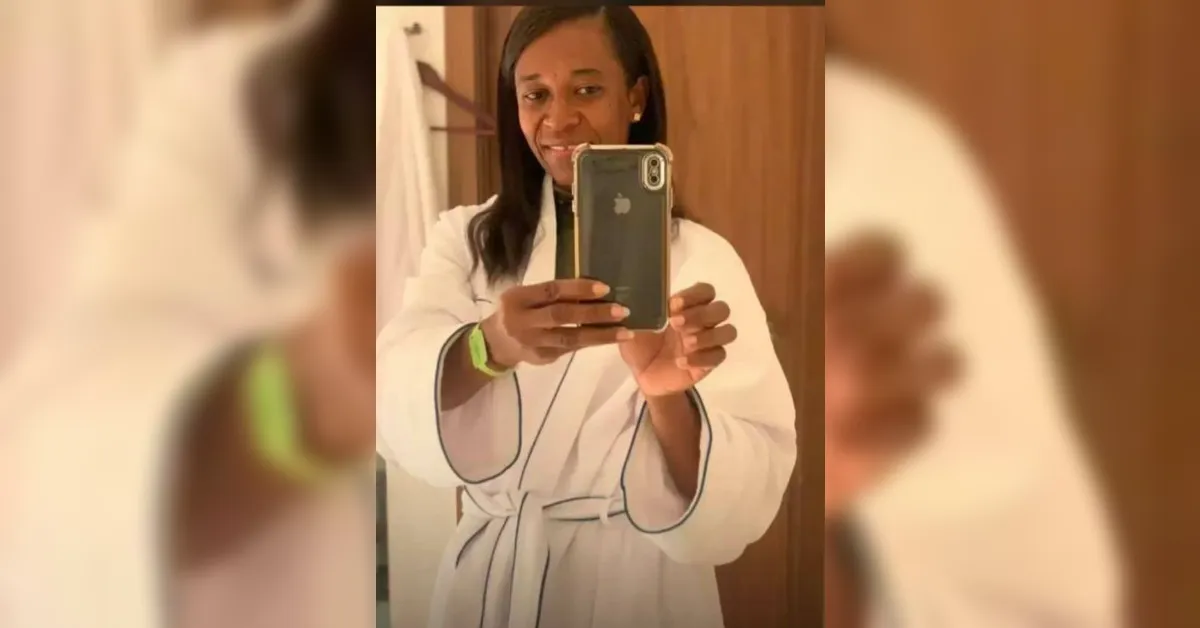 Woman in a white bathrobe taking a mirror selfie with a smartphone, smiling.