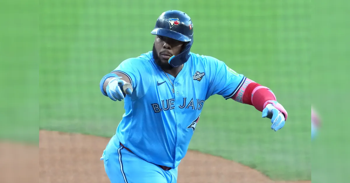 Toronto Blue Jays baseball player in a blue uniform, helmet, and elbow guard, extending an arm as he runs on the field.