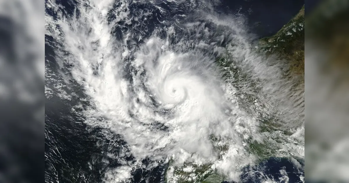 Satellite view of a fierce hurricane with a distinct eye centered over the sea, swirling clouds approaching the coast.