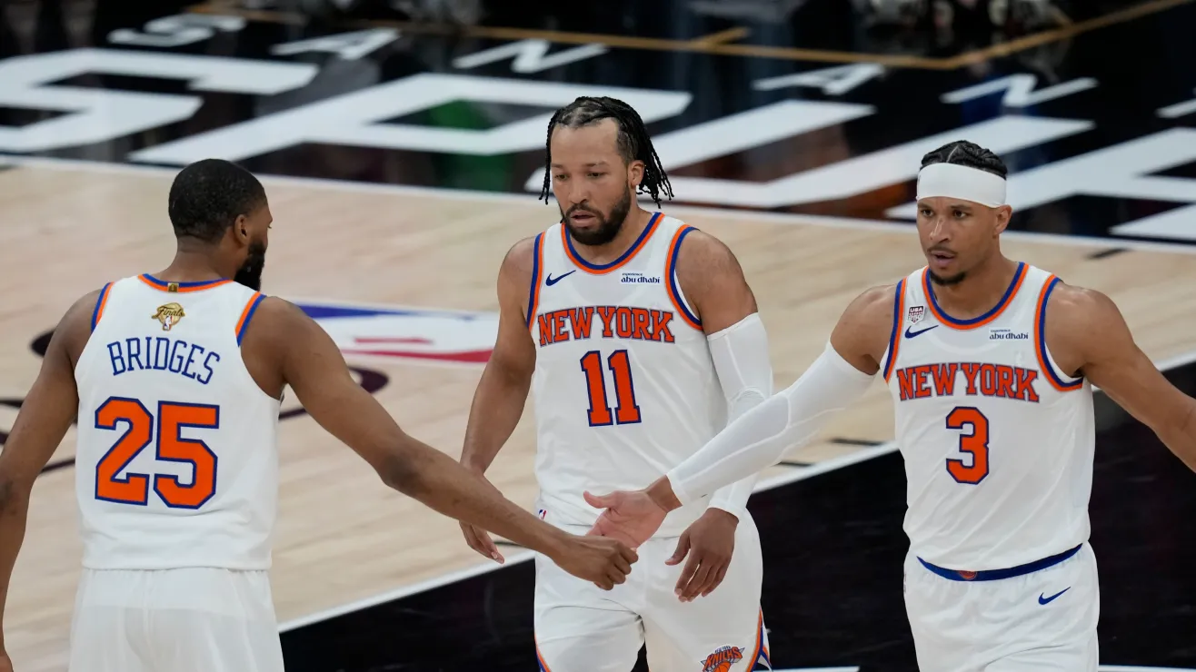 Three New York Knicks players (#25, #11, #3) high-five on a basketball court during a game.