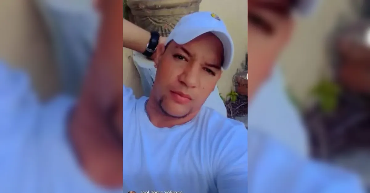 Man recording a selfie video outdoors, wearing a light blue shirt and a white cap while touching the back of his head pitifully?
