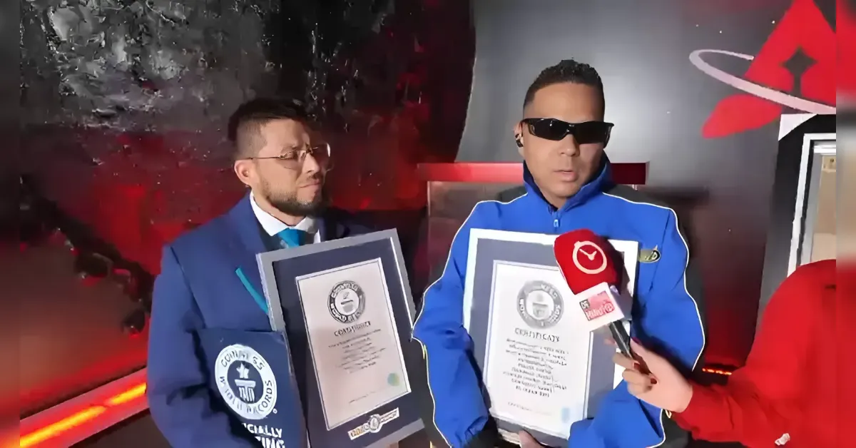 Two men in formal attire hold large framed certificates during an interview, a red microphone near them.