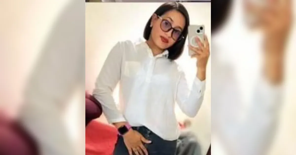Woman taking a mirror selfie in a white shirt and dark jeans, wearing large glasses.