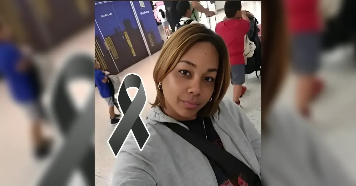 Selfie of a woman in a gray jacket standing in a crowd, with a large black remembrance ribbon overlaid on the image.