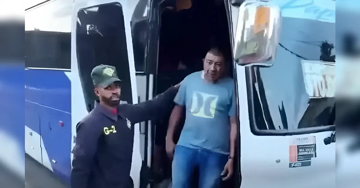 Security officer in uniform helps a man exit a white bus with blue accents at the doorway.