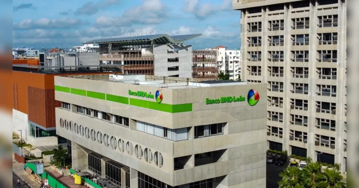 Banco BHD León bank building with a bright green stripe, circular windows, and an urban backdrop.