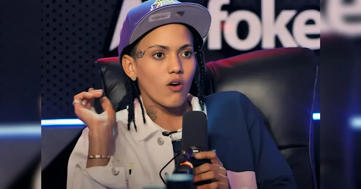 Woman in a cap and white jacket speaks into a microphone in a podcast studio.