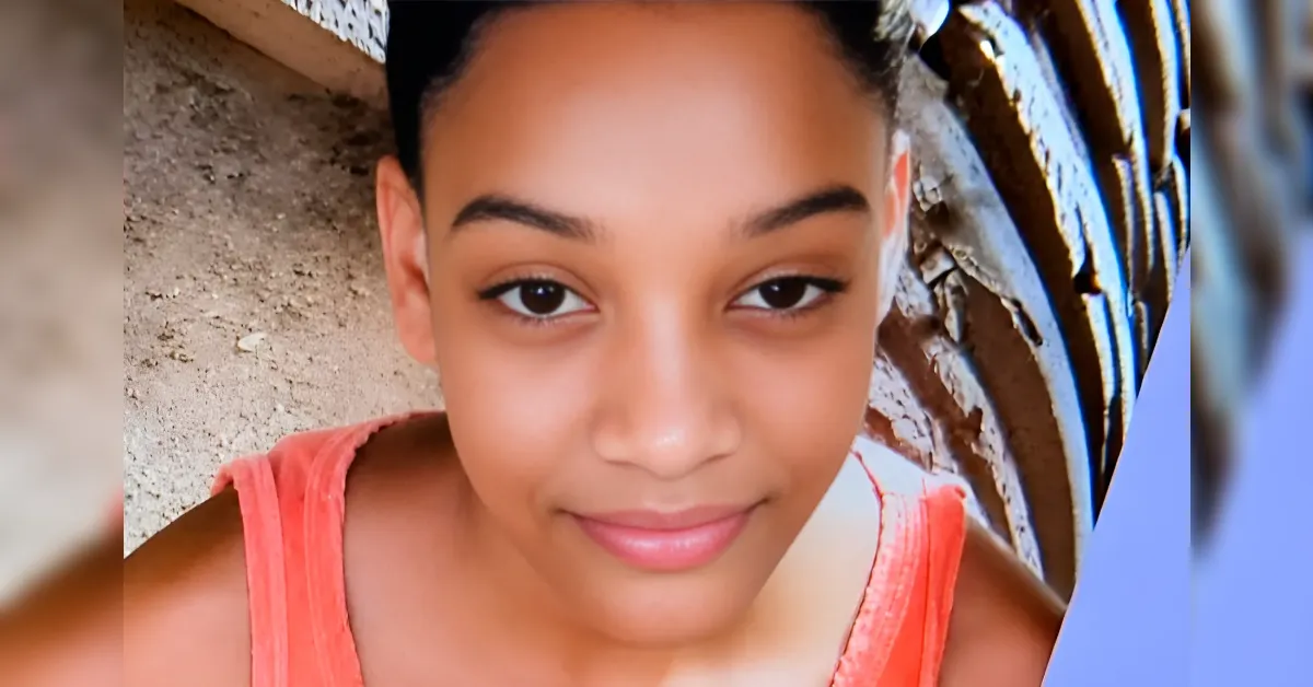 Close-up of a smiling young woman wearing a coral tank top outdoors.