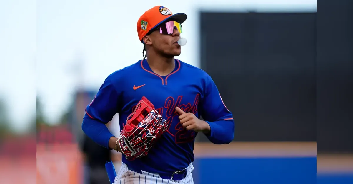 Baseball player in a blue New York–style uniform runs with a red glove and orange cap, wearing mirrored sunglasses and a bubble gum bubble.