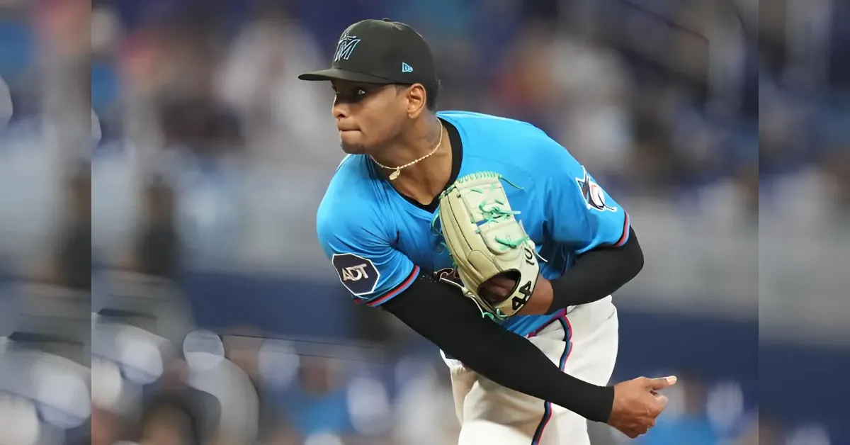 Baseball pitcher in a blue jersey mid-throw with glove up, on the mound during a game.
